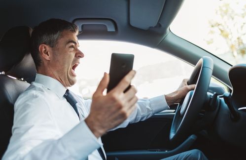 男子脚伸车窗外边玩手机边开车